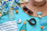 Produits de beauté et affaires de plage posés sur une serviette bleue